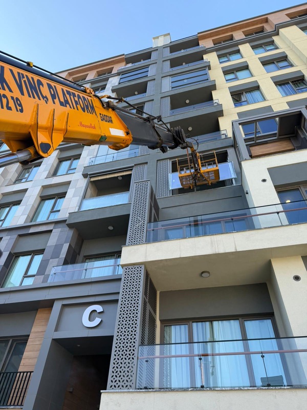 Yeni bir konut binasının balkon cephesinde sepetli platform